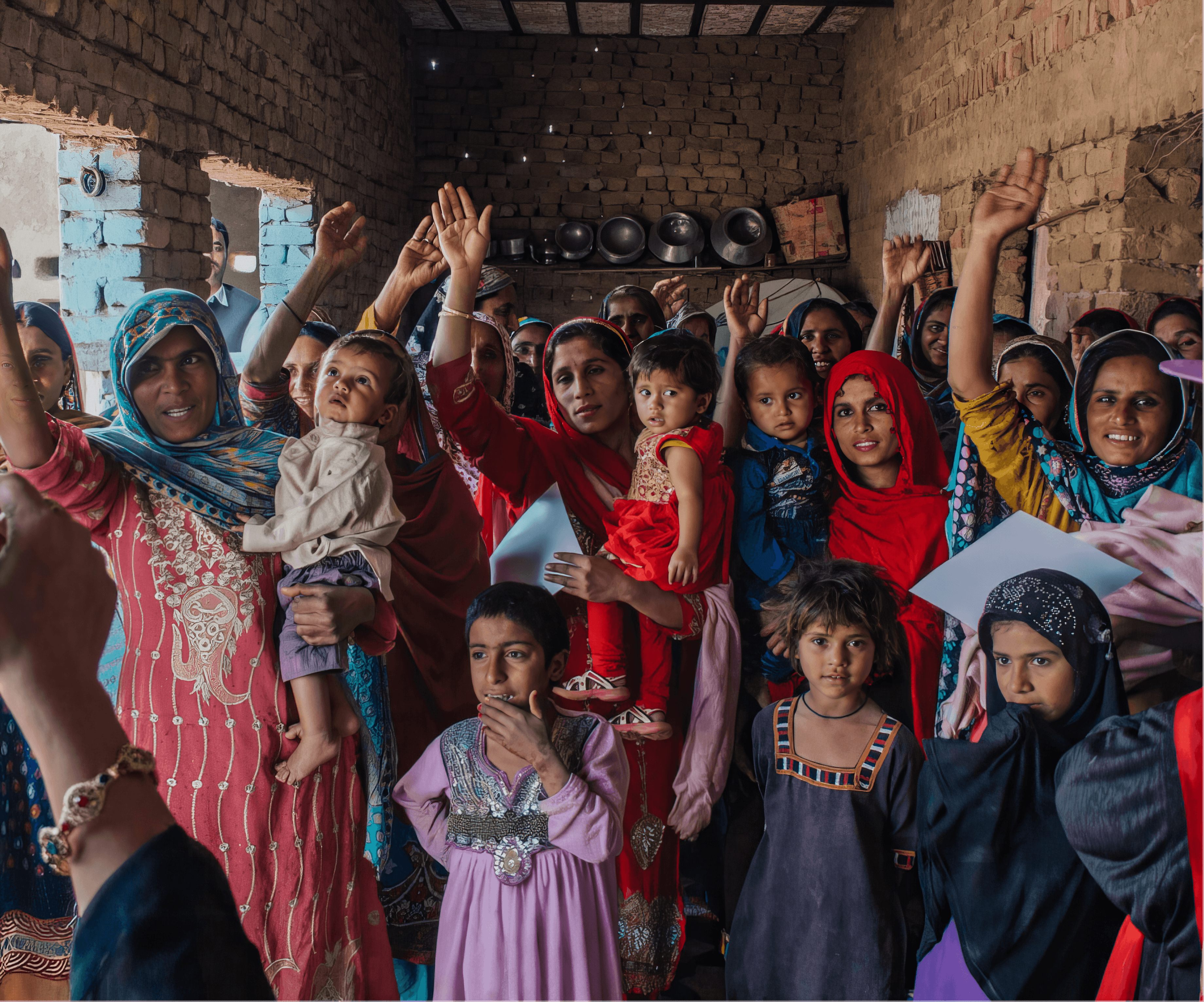 Community women and children raising hands in active participation during a workshop
